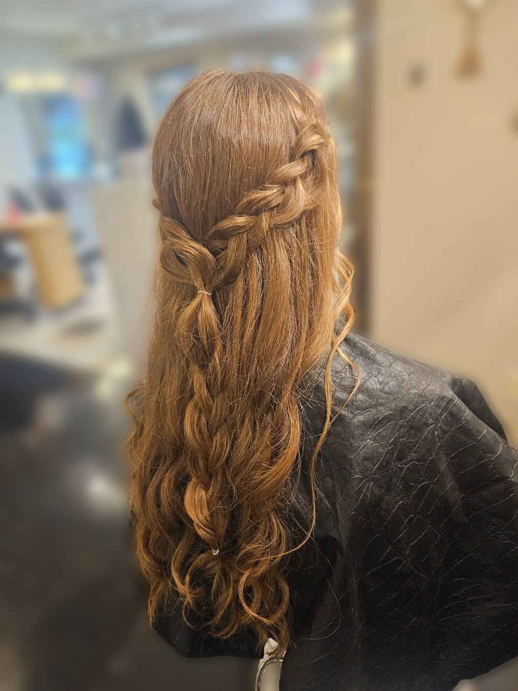 Long copper hair styled in a half-up braid with loose waves